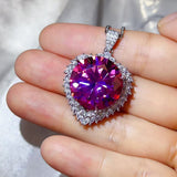 20 Carat Moissanite 925 Sterling Silver Pendant Necklace held in hand with pink gemstone and diamond accents.